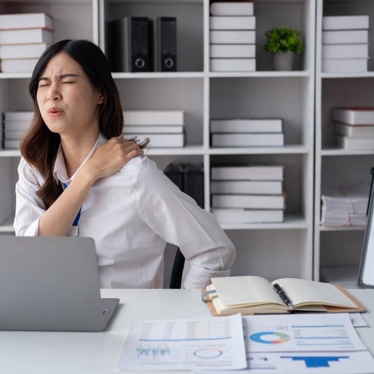 Asian businesswomen suffer from shoulder pain from working too much in an office.